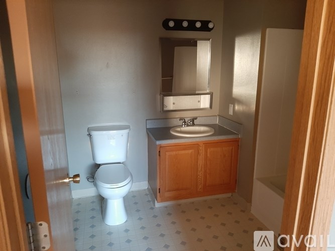 A bathroom with a toilet, sink, and mirror.