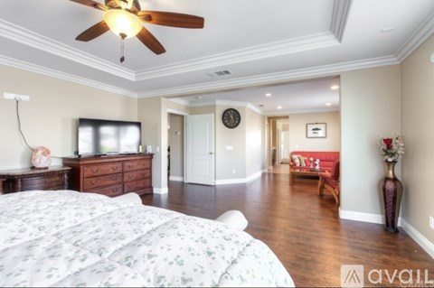 A bedroom with a large bed and a ceiling fan.