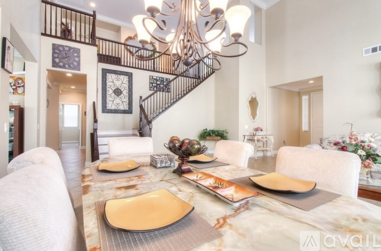 A dining room with a marble table and a chandelier.
