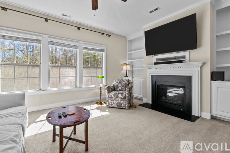 A living room with a fireplace and a flat screen TV mounted above it.