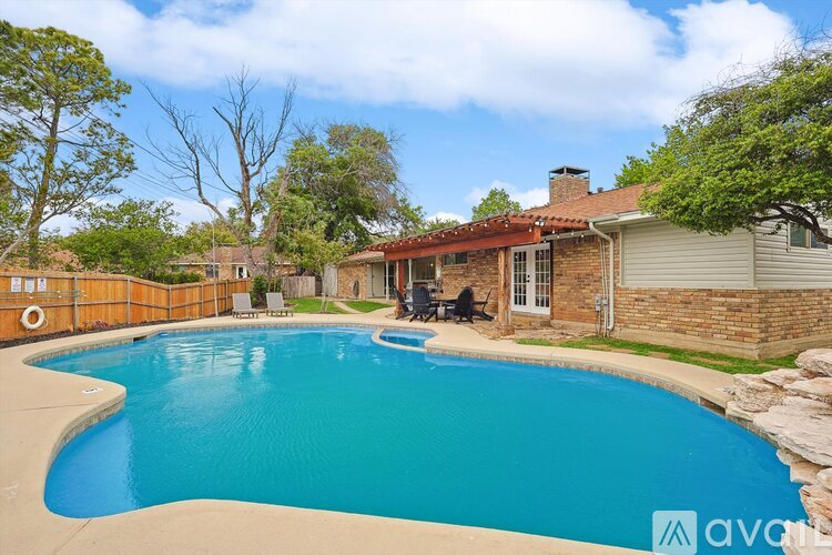 A swimming pool in a backyard with a house and trees in the background.