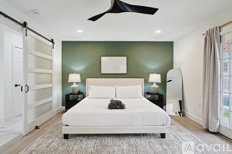 A bedroom with a white bed and a ceiling fan.