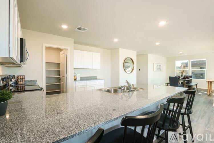 A modern kitchen with granite countertops and black barstools.