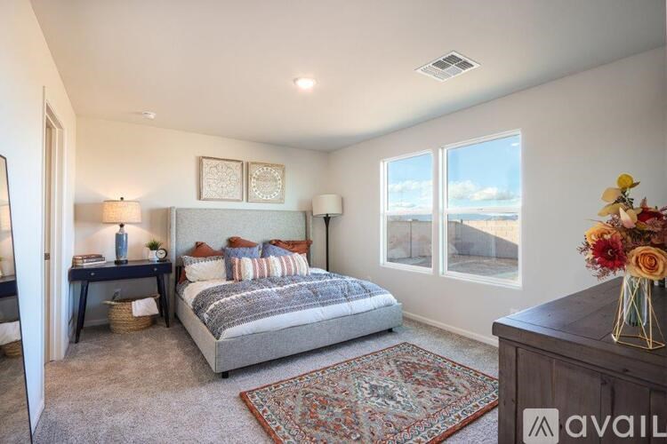 A bedroom with a large bed and a view of the outdoors through the windows.