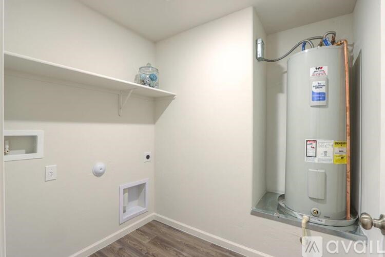 A room with a wall-mounted shelf and a water heater installed in the corner.
