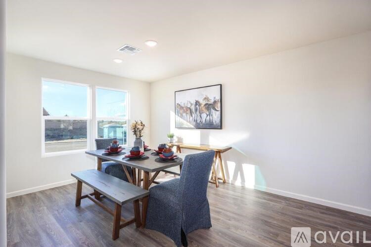 A dining room with a table set for two and a painting of camels on the wall.