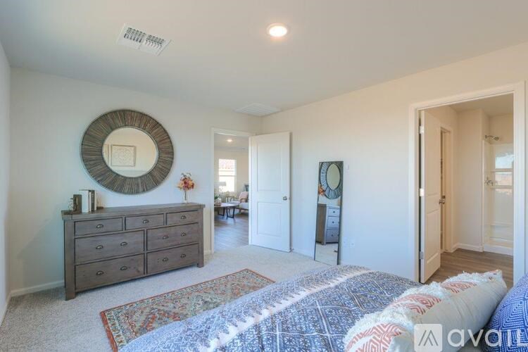 A bedroom with a large bed and a dresser with a mirror above it.