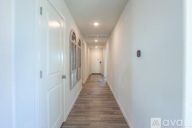 A long hallway with white walls and wood flooring.
