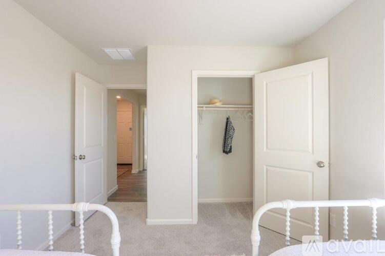 A white bedroom with a bed on the left and a wardrobe on the right.