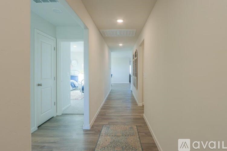 A hallway with a rug on the floor and a door on the left.