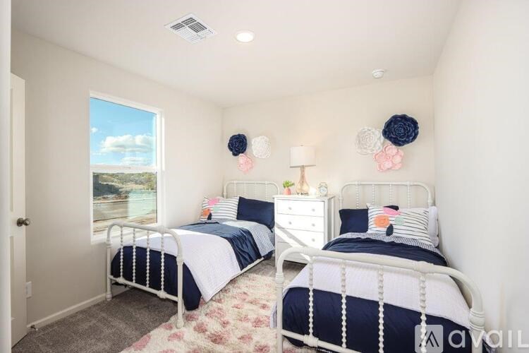 A bedroom with two beds and a window showing a view of the sky.