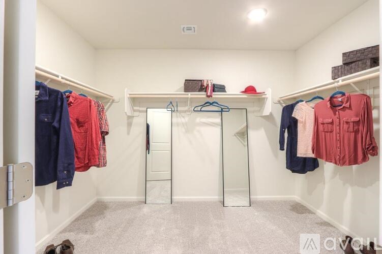 A white closet with clothes hanging on hangers and a white door.