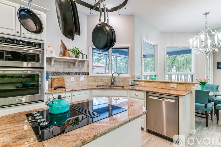 A kitchen with a teal kettle on the stove.