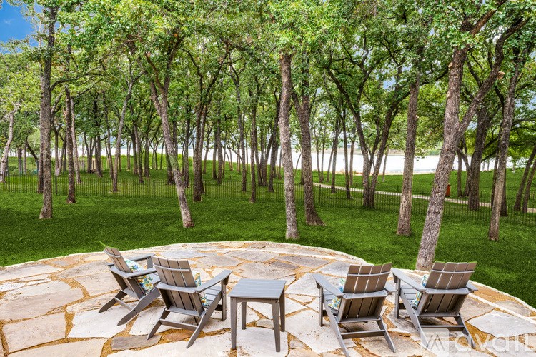 A patio with chairs and a table surrounded by trees.