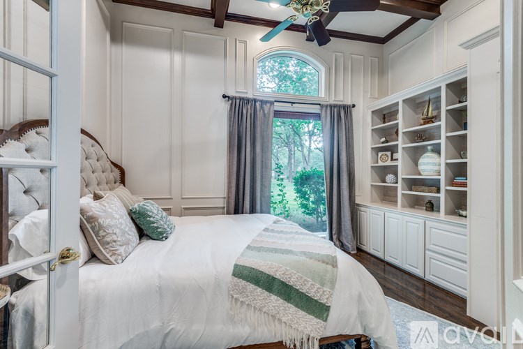 A bedroom with a bed, a window with a curtain, and a ceiling fan.