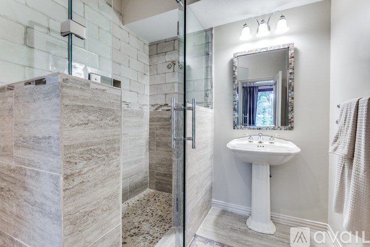 A bathroom with a sink, mirror, and shower.