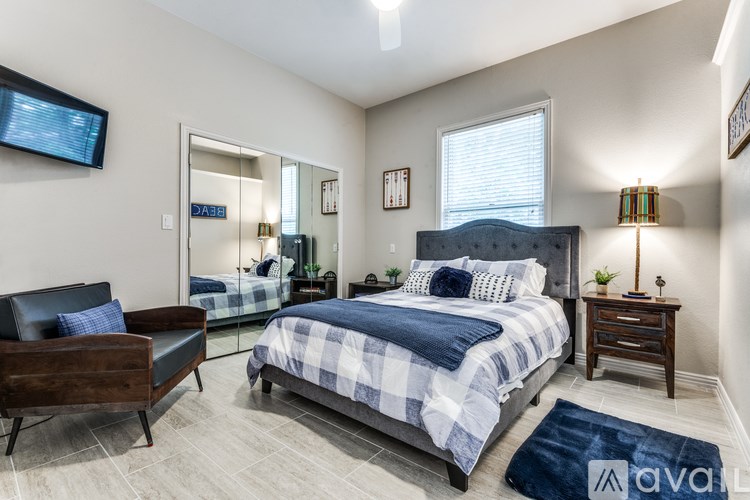 A bedroom with a bed, a chair, and a mirror.