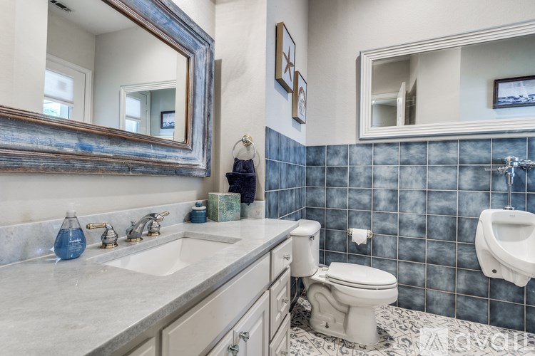 A bathroom with a blue tiled wall and a white toilet.