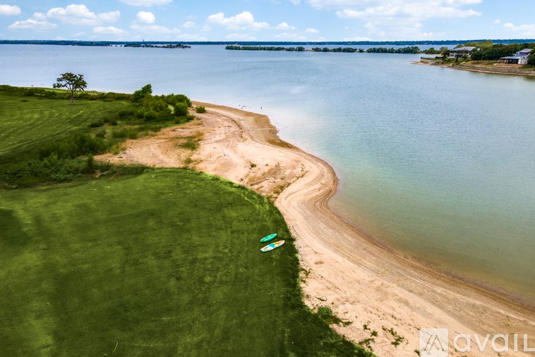 A beach with a green grassy area and a blue kayak.