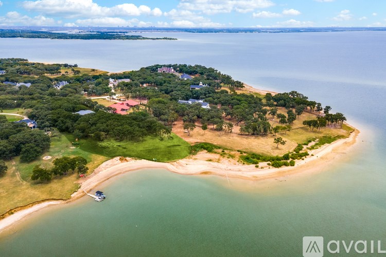 A small island with a beach and a few buildings is surrounded by water.