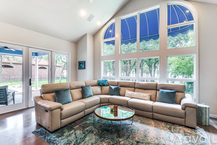 A living room with a tan couch and a glass coffee table.