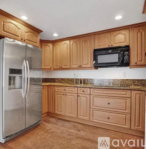A kitchen with wooden cabinets and a stainless steel refrigerator.