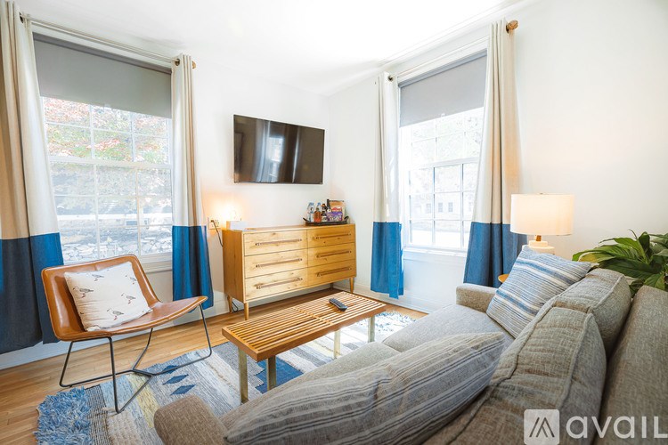 A living room with a grey couch, a wooden coffee table, and a chair with a white cushion.