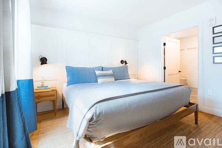 A bedroom with a large bed and a nightstand with a lamp.