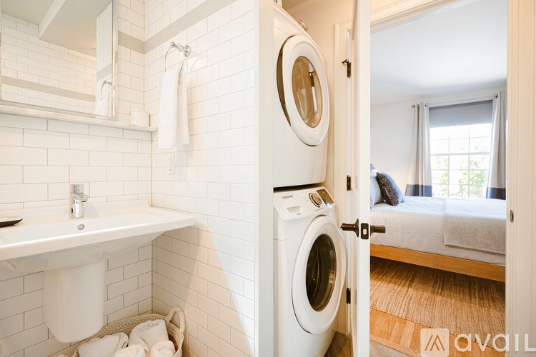 A white tiled bathroom with a washer and dryer built into the wall.