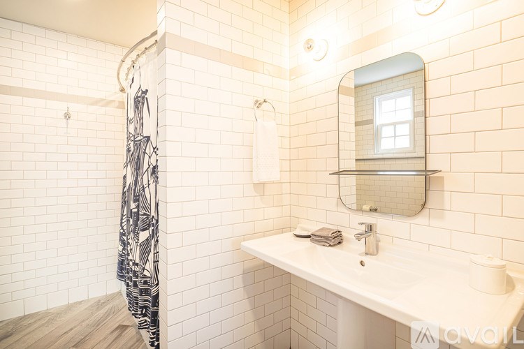 A bathroom with a white tiled shower and a white sink.