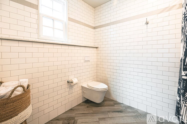 A white toilet sits in a bathroom with white tiled walls.