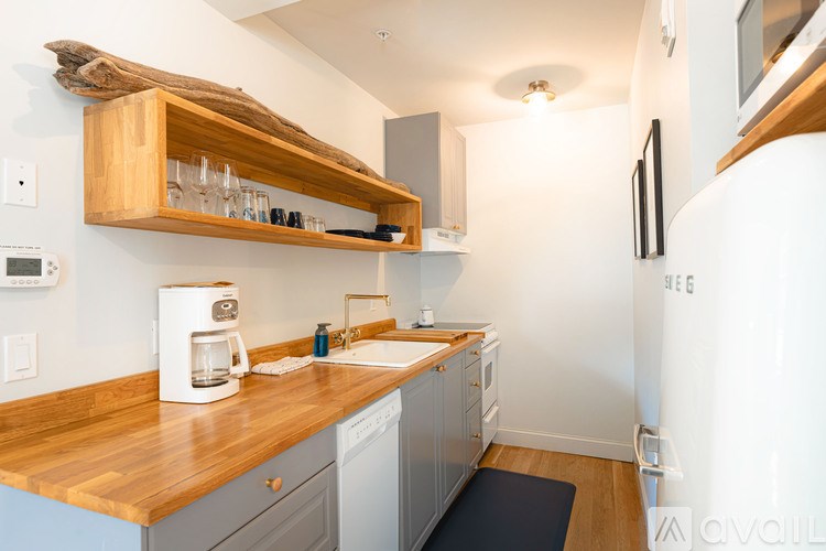 A kitchen with a wooden counter top and a white coffee maker.