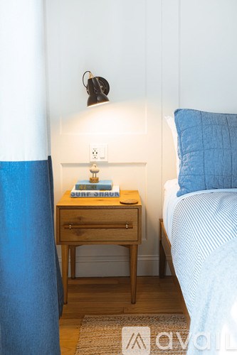 A bedroom with a bed, nightstand, and a lamp.