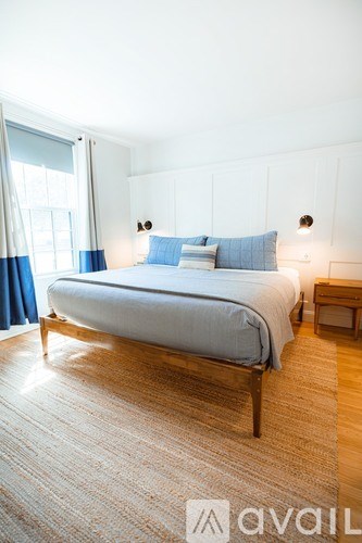 A bedroom with a bed, nightstand, and window.