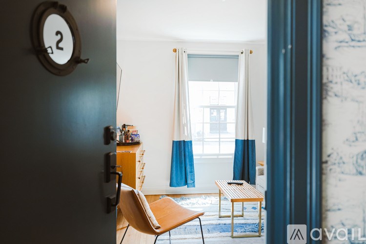 A room with a blue door and a round clock on the wall.