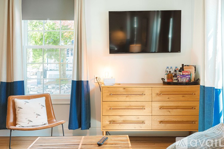 A living room with a chair, a dresser, and a window.
