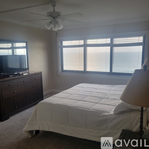 A bedroom with a large bed, a dresser, and a television.