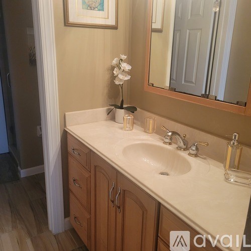 A bathroom with a sink, mirror, and a vase of flowers.