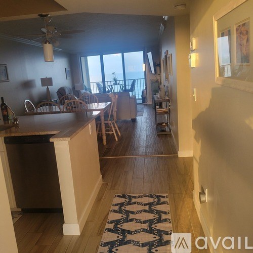 A kitchen with a refrigerator, sink, and a dining table with chairs.
