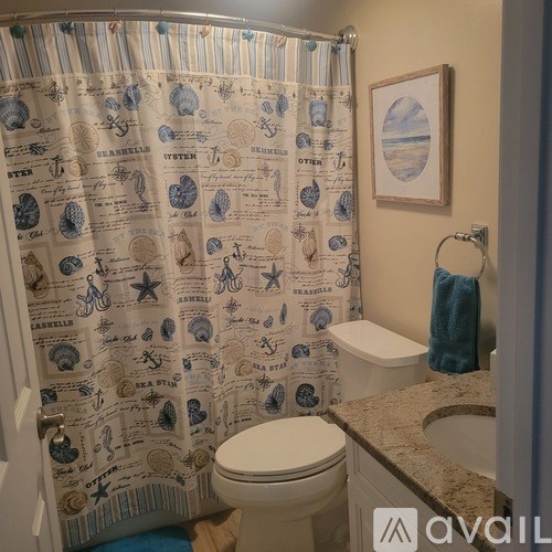 A bathroom with a shower curtain that has sea shells on it.