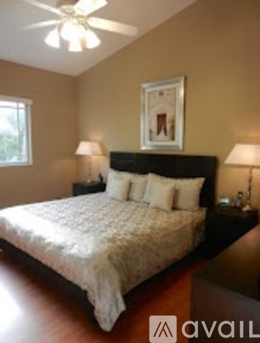 A bedroom with a bed, two lamps, and a picture on the wall.