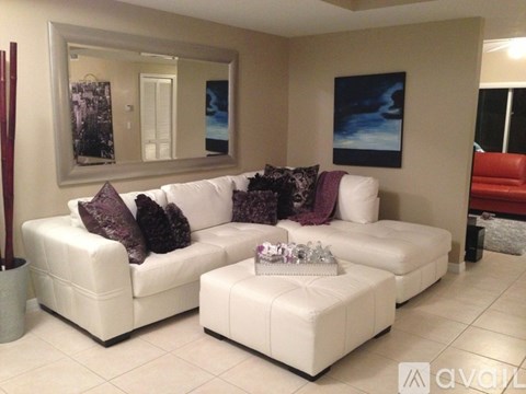 A living room with a white couch and a mirror on the wall.