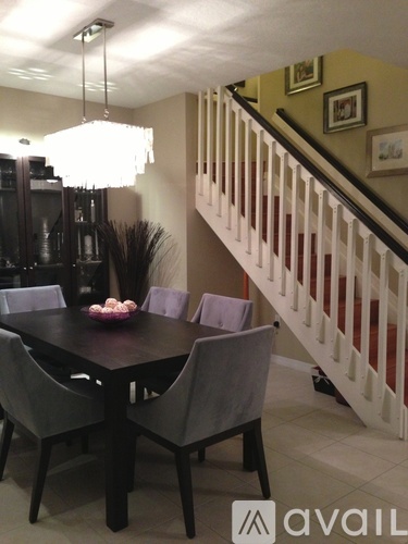 A dining room with a table and chairs and a staircase.