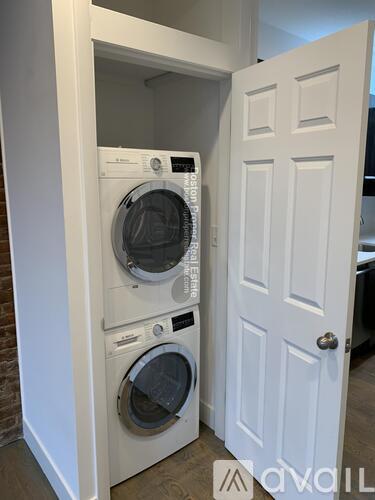 A white door is open to reveal a washing machine tucked inside.