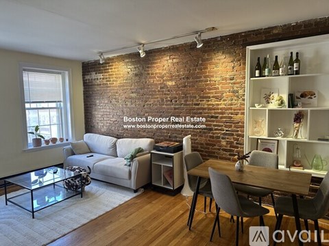 A living room with a brick wall and a dining table.