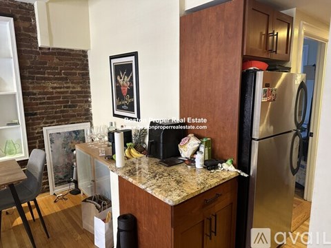 A kitchen with a refrigerator, a counter, and a chair.