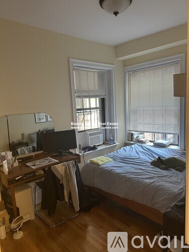 A bedroom with a bed, desk, and window.