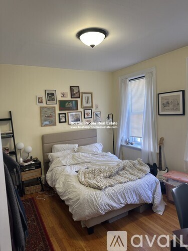 A bedroom with a bed, nightstand, and pictures on the wall.