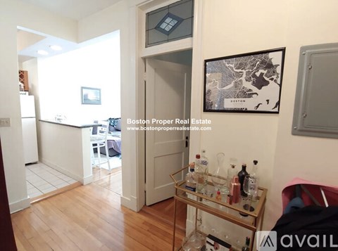A kitchen area with a refrigerator, a table with bottles, and a map of Boston on the wall.