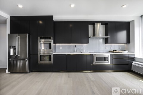 A modern kitchen with black cabinets and stainless steel appliances.